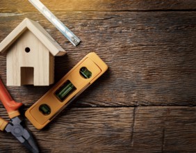 A detailed layout of miniature wooden houses accompanied by various tools on a textured wooden