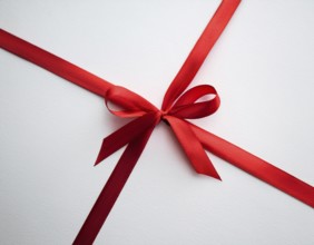 A beautifully wrapped gift box adorned with red satin ribbons forming a bow, contrasting against a