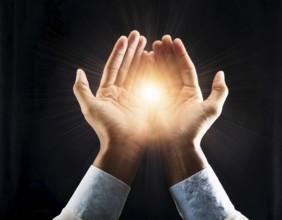 Hand holding light ray in the darkness, hope concept. Light in hands. Freedom and spirituality