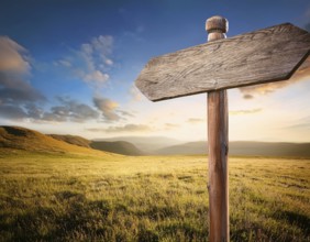A weathered wooden sign stands in a vast setting, evoking feelings of adventure. The clear blue sky