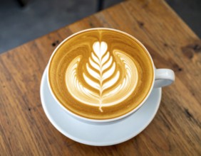 A cozy café latte with heart foam art on wooden table, representing comfort, relaxation, and warm