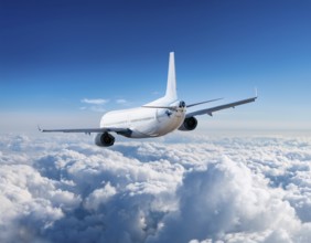 Airplane soaring over a field of clouds in a bright blue sky, AI generated