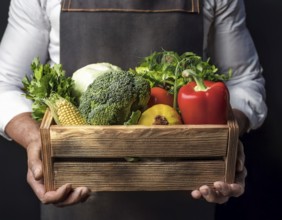 Man holding wooden crate with vegetables. Wooden box filled with fresh food products and ready for