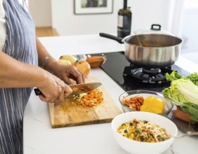 A cozy kitchen scene showing only hands of a couple preparing food, chopping vegetables, and