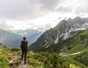 Traveler with backpack overlooking mountain valley at sunrise, symbolizing adventure, exploration,
