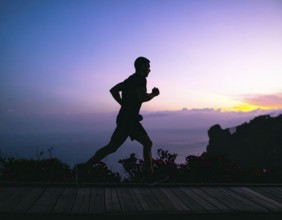 A cinematic silhouette of an athletic man running, representing fitness, endurance, wellness, and