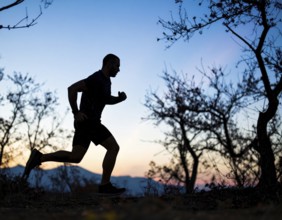 A cinematic silhouette of an athletic man running, representing fitness, endurance, wellness, and