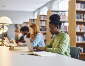 University students studying with open books and laptops, symbolizing education, collaborative