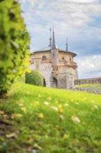 Charming turret on a green meadow in front of a slightly cloudy sky creates a romantic atmosphere,