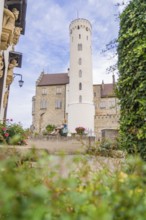 Woman sitting quietly in a castle garden in front of a high tower, Lichtenstein Castle,