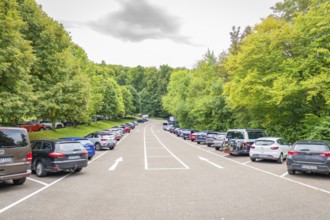 A long car park, lined with many cars and lush green trees, Lichtenstein Castle, Lichtenstein,