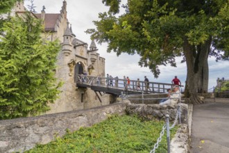 People on a stone bridge leading to a castle, surrounded by trees, Lichtenstein Castle,