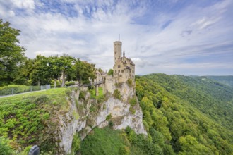 Impressive castle stands on a lush cliff, surrounded by mountains and sky, Lichtenstein Castle,