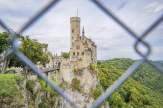 Castle on a hill, framed by green forest and viewed through a lattice, Lichtenstein Castle,