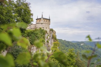 An impressive castle perched high on a cliff with sweeping views over the green landscape,