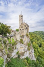 Castle stands impressively on a green cliff under a blue sky, Lichtenstein Castle, Lichtenstein,