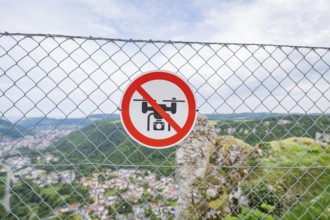 Lattice fence with drone prohibition sign in front of a wide panoramic view over the landscape,