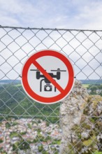 Sign on the fence indicating a drone ban, with a view of the landscape below, Lichtenstein Castle,