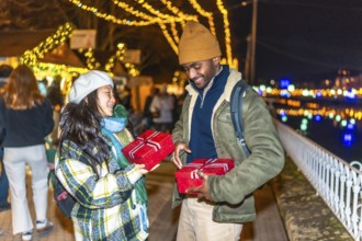 Young multiethnic couple exchanging christmas gifts at a christmas market, enjoying winter holidays