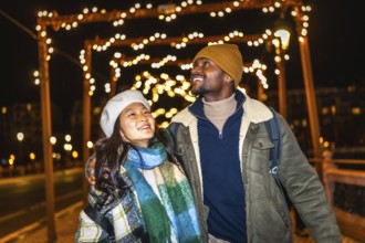 Multiethnic couple enjoying the enchanting glow of christmas lights while strolling through a