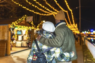 Young multiethnic couple walking hand in hand, sharing warm hugs amidst the glowing lights of a