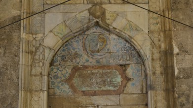 Decorated arch with faded inscriptions and ornaments on a stone background, Recep Pasha Mosque, Old