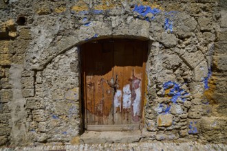 Weathered wooden door in an ancient stone wall decorated with blue accents, Turkish Quarter, Rhodes