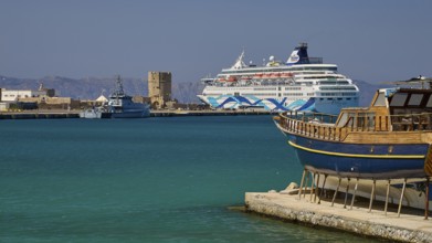 Coastal view with traditional boat and cruise ship in the harbour in sunny weather, Rhodes Old