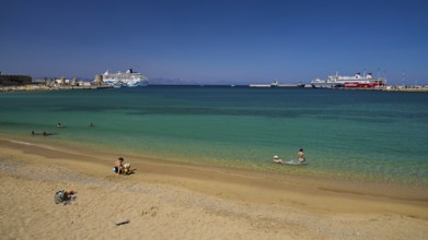 Clear water and beaches with a view of the harbour and several ships on a sunny day, Sachtouri