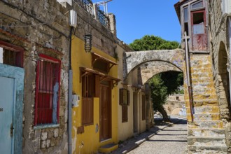 Narrow alley with old houses, yellow facades and colourful windows, Jewish Quarter, Rhodes Old