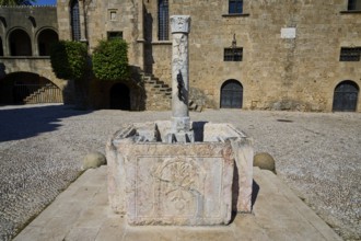 Medieval sandstone fountain with stone column in a historic ruin in the sunshine, Rhodes Old Town,