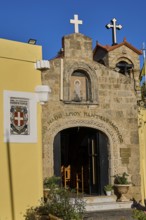 Church of Agios PanteleimoChurch entrance with icon painting and crosses, yellow wall in the