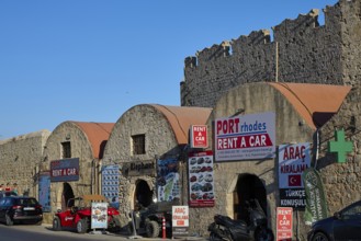 Outside the fortress walls, warehouses, row of buildings with car hire signs under historic stone