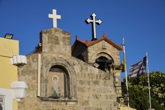 Church of Agios Panteleimon, stone church with crosses and flags in the background under a blue