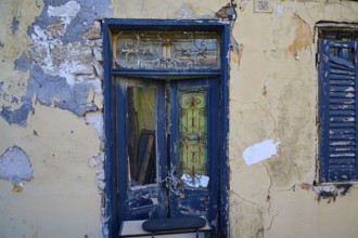 Weathered door and shutters on an old, dilapidated building with peeling paint, Rhodes Old Town,