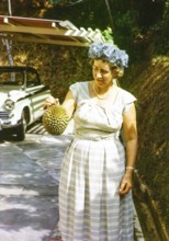 British expatriate woman holding a durian fruit, durio zibethinus, she is wearing smart clothing of