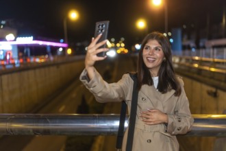 Young woman smiling and taking a selfie with a smartphone at night, capturing moments of connection