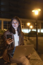 Young woman engaging in remote work and communication, looking at her smartphone while holding a