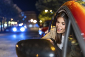 Woman looking out car window enjoying a vibrant city night with blurred lights creating bokeh,
