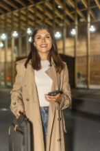 Young businesswoman traveling and commuting, holding a smartphone and briefcase, smiling while