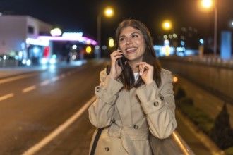 Young woman smiling and communicating on a smartphone, walking along a vibrant urban street during