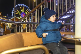 Young child enjoying a carousel ride at a vibrant christmas market in bayonne, france, creating a