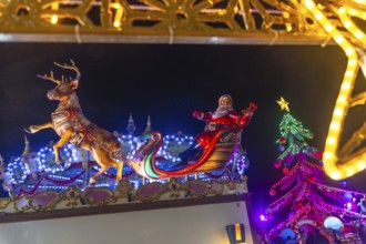 Santa claus figurine waving on a sleigh pulled by a reindeer at the bayonne christmas market in