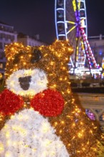 Festive christmas bear decoration shines brightly in bayonne, france, with a ferris wheel adding to