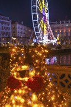 Luminous christmas bear decoration shining brightly in bayonne, france, with a ferris wheel and