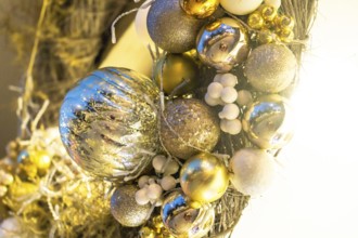 Close up of a christmas wreath with gold and silver shiny ornaments and white berries, adding a
