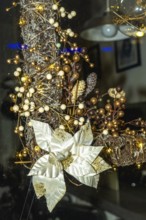 Festive christmas wreath adorned with golden and white poinsettia, berries, and string lights