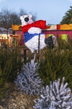 Illuminated polar bear with red scarf and blue vest ice skating at a christmas market in bayonne,