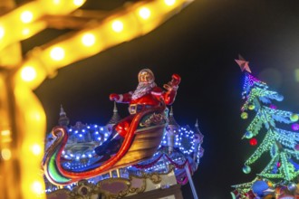 Santa claus sitting on his sleigh and waving to people during christmas night in bayonne, france,