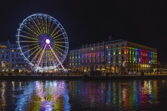 Colorful ferris wheel and city hall reflecting in the river nive in bayonne, france, during